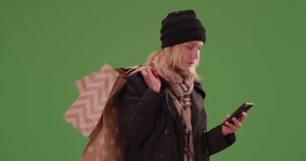Egy nő, aki üdülési jogra vár, bevásárló táskákkal a zöld képernyőn. Zöldfelületen karcolt vagy összeállított. - Felvétel, videó