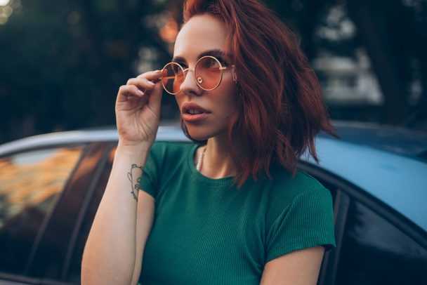 Young woman in glasses posing near car - Photo, Image