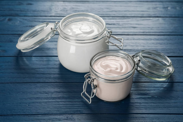 Jars of tasty organic yogurt on blue wooden table - Foto, imagen