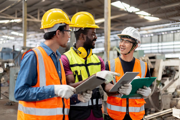 Trzech inżynierów przemysłowych nosi twarde kapelusze i mundury, wykorzystując projekt fabryki w przemyśle ciężkim. Kierownik nauczający pracowników pracy. - Zdjęcie, obraz