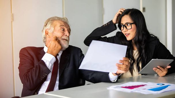 anziano uomo d'affari e donna d'affari seduti in una riunione e controllare documenti e quaderni su una scrivania in una sala riunioni. - Foto, immagini