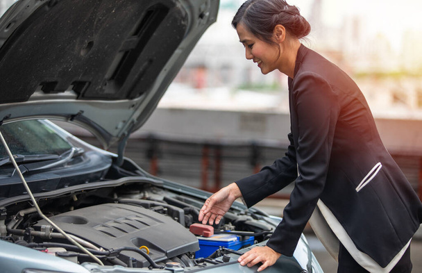 A businesswoman checks a broken car on the side of the road and she is stressed that her car is broken. - Foto, Imagen