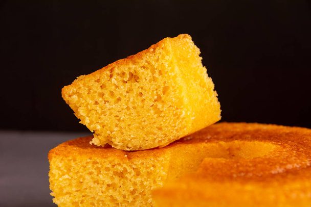 Кусок домашнего круглого кукурузного торта, веганский и здоровый вкусный торт (Bolo de Fuba), Close Up View, Black Background - Фото, изображение
