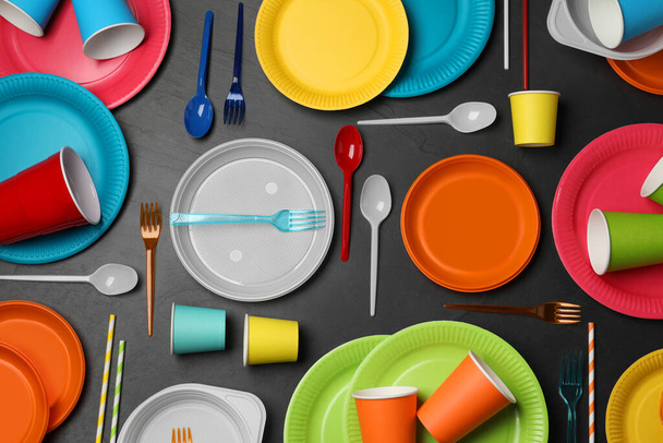 Flat lay composition with different disposable tableware on black background - Foto, Imagen