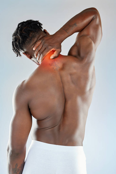 I know just how to get rid of the pain. Studio shot of a muscular young man experiencing discomfort in his neck - Fotó, kép