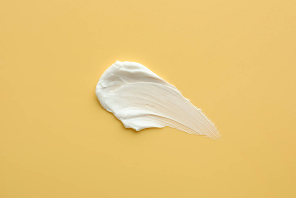 Sample of face cream on yellow background, top view - Φωτογραφία, εικόνα