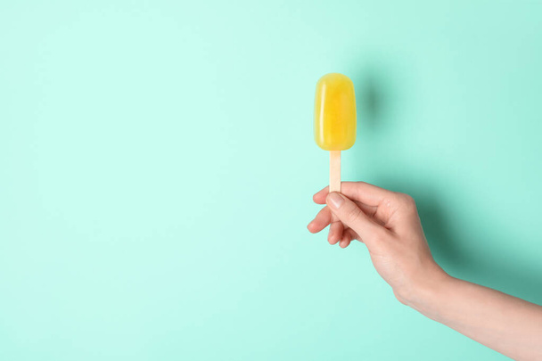 Woman holding delicious ice pop on turquoise background, closeup view with space for text. Fruit popsicle - Photo, Image