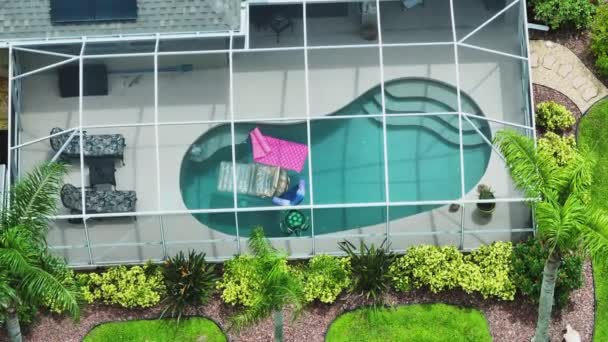 Vista superior de la casa privada americana contemporánea con el recinto exterior del lanai sobre la gran piscina. Concepto de vida al aire libre y pasar un buen rato en el agua de la piscina en el cálido sol de verano de Florida. - Metraje, vídeo