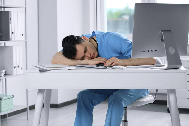 Exhausted doctor sleeping at workplace in hospital - Fotó, kép