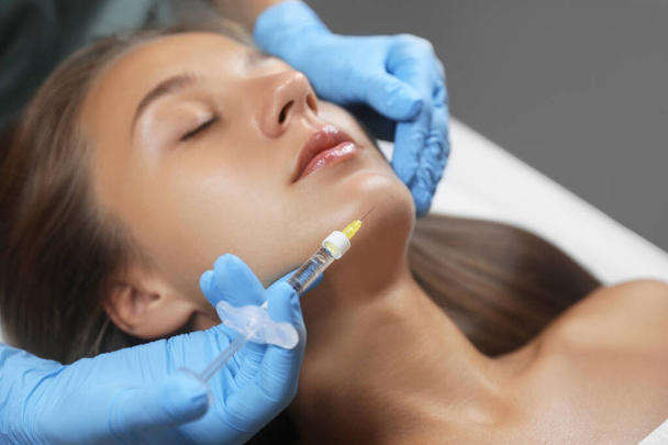 Beautiful woman getting facial injection in salon - Фото, изображение