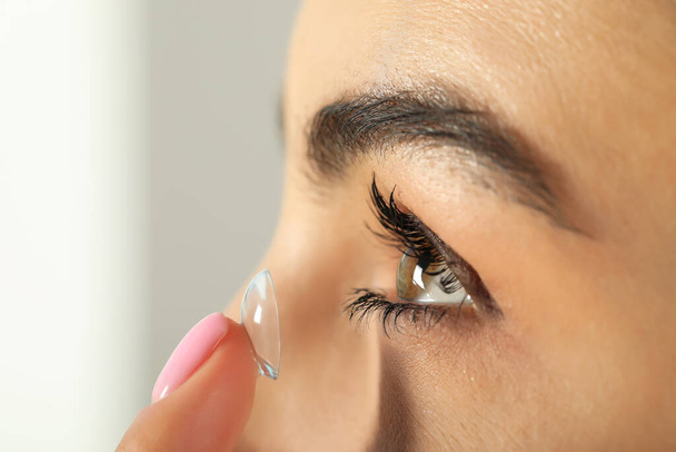 Young woman putting contact lens in her eye, closeup - Foto, Imagen