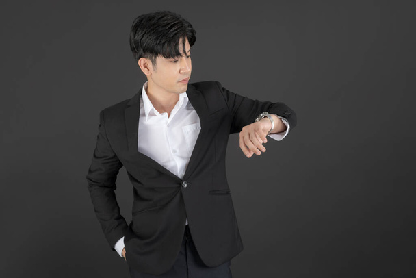 Business man wearing a black suit raising hands doing different gestures on a dark background - Photo, Image