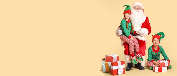 Santa Claus and little elf kids with gifts on beige background with space for text - Photo, Image