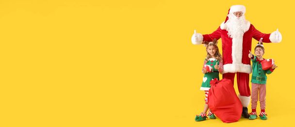 Noel Baba 'lı şirin küçük elfler ve sarı arka planda mesaj için yeri olan Noel hediyeleri. - Fotoğraf, Görsel