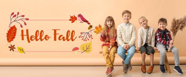 Cute little children sitting on bench and text HELLO FALL on beige background - Photo, Image