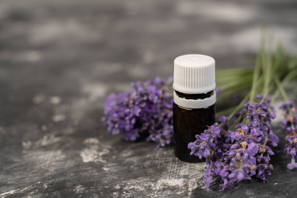 Aromatherapie tools, olieflessen en lavendelbloemen. Fles etherische olie en lavendelbloemen op grijze achtergrond. aromatherapie spa massage concept. Lavendeloleum - Foto, afbeelding