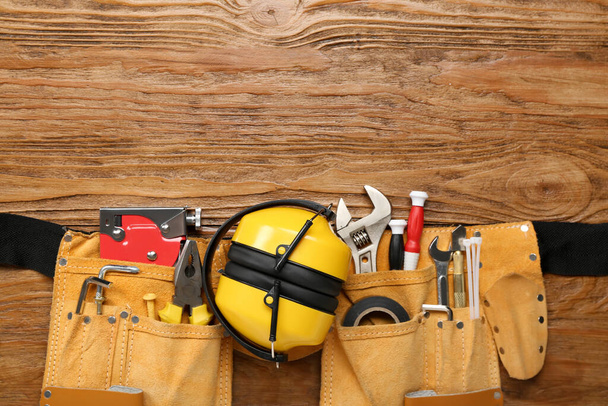 Táska építőipari szerszámokkal és hallásvédő eszközökkel fából készült háttéren - Fotó, kép
