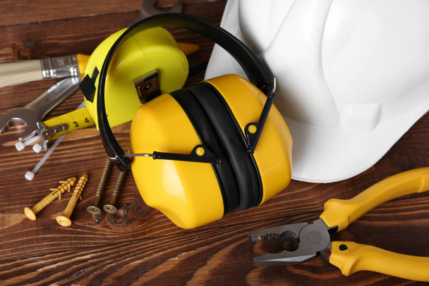 Protectores auditivos con herramientas de construcción sobre fondo de madera oscura, primer plano - Foto, imagen
