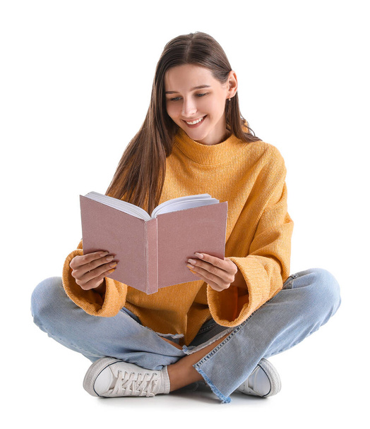 Beautiful woman in yellow sweater reading book on white background - Фото, изображение