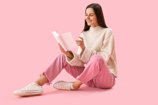 Schöne Frau liest Buch auf rosa Hintergrund - Foto, Bild