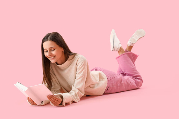Schöne Frau liest Buch auf rosa Hintergrund - Foto, Bild