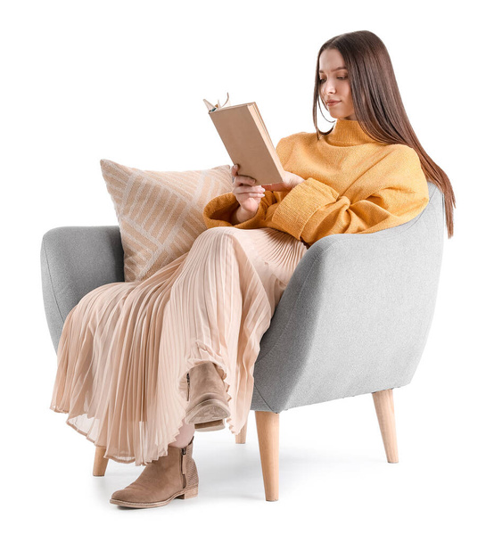 Joven mujer leyendo libro en acogedor sillón sobre fondo blanco - Foto, Imagen