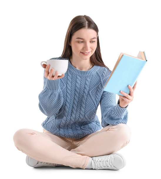 Junge Frau im blauen Pullover mit Tasse Kakao-Lesebuch auf weißem Hintergrund - Foto, Bild