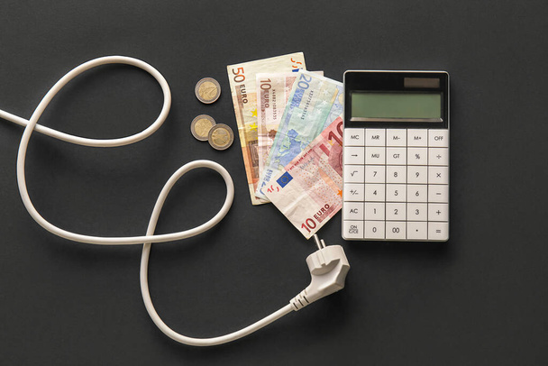 Dinero con enchufe y calculadora sobre fondo negro. concepto de temporada de calefacción - Foto, Imagen