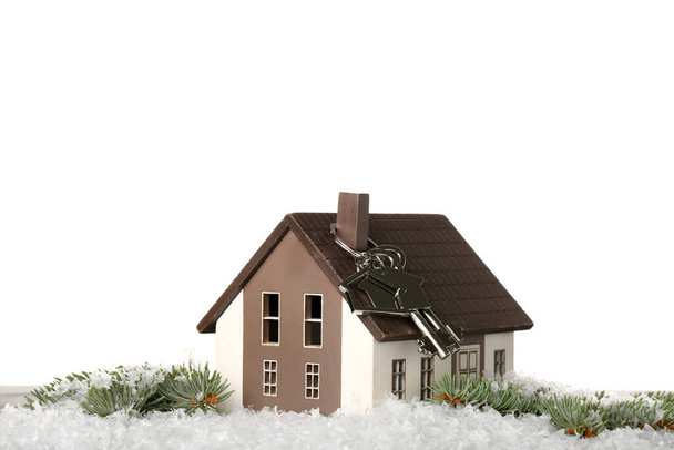 Modelo de casa con llave, ramas de abeto y nieve sobre la mesa sobre fondo blanco - Foto, Imagen