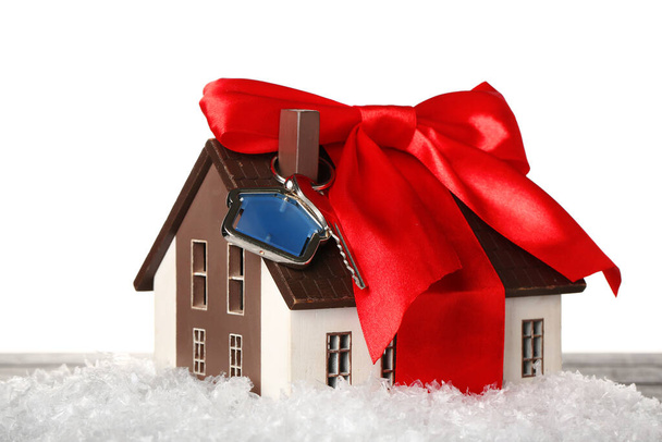 House model with key, bow and snow on table against white background - Photo, Image