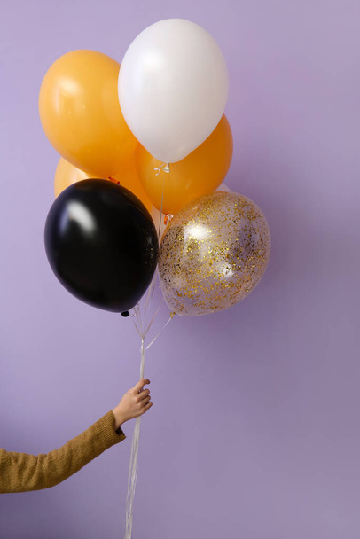 Woman with Halloween balloons near violet wall - Foto, imagen