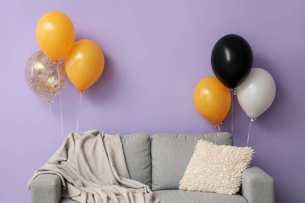 Kanapa z balonami Halloween w pobliżu fioletowej ściany - Zdjęcie, obraz