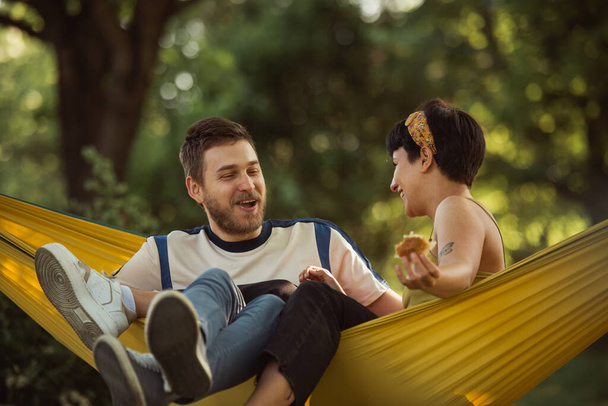 Joli couple se réunissant assis sur un hamac jaune dans le parc - Photo, image