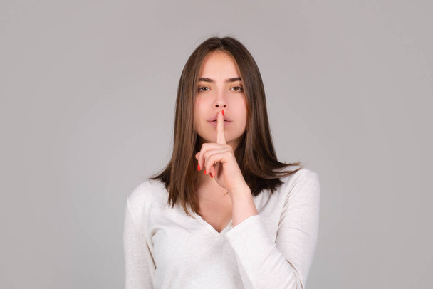 Shh, womens secrets. Woman showing secret sign. Female with finger in mouth. Closeup portrait of young woman is showing a sign of silence with shhh - Photo, image
