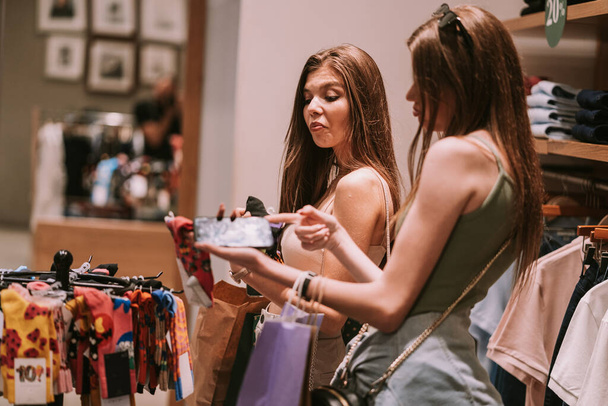 Две красивые девушки ищут носки в магазине моды в торговом центре - Фото, изображение