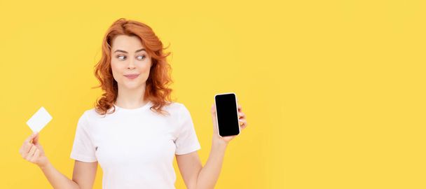 Γυναίκα απομονωμένη προσωπογραφία, πανό με ψεύτικο χώρο αντιγραφής. χαρούμενη γυναίκα που δείχνει πιστωτική ή χρεωστική κάρτα και smartphone για να κάνει online αγορές, cyber Monday - Φωτογραφία, εικόνα