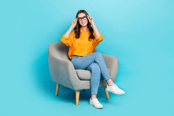 Full size portrait of cheerful gorgeous person sit chair hands touch glasses isolated on blue color background. - Foto, Imagem