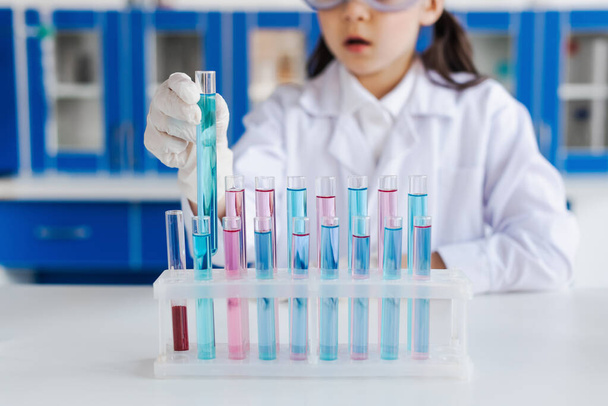 bijgesneden beeld van wazig meisje in latex handschoen houden reageerbuis in laboratorium - Foto, afbeelding