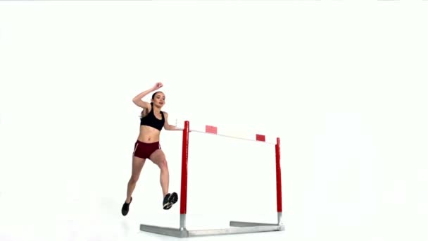 Female athlete jumping over hurdle - Materiał filmowy, wideo