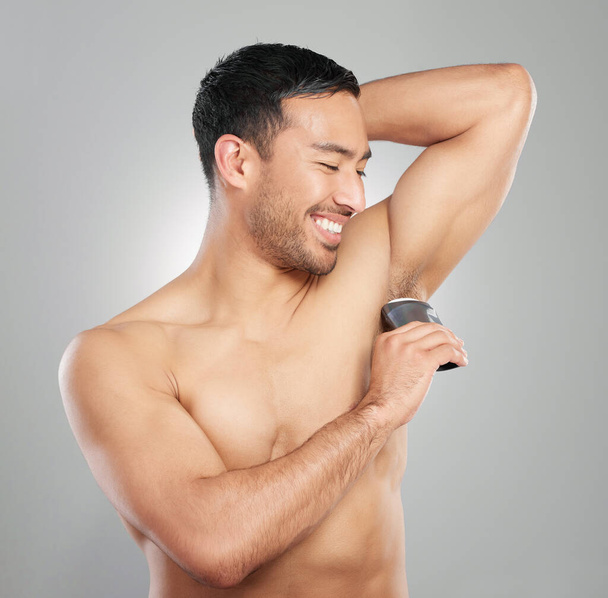 No sweat, Ive got this. Studio shot of a handsome young man applying deodorant against a grey background - Photo, Image