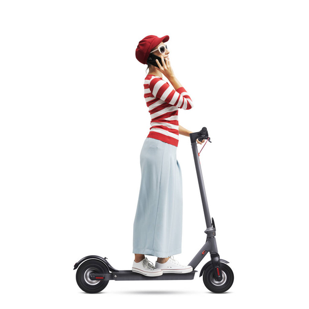 Young happy woman riding a electric scooter and having a phone call with her smartphone, white background - Foto, Imagem