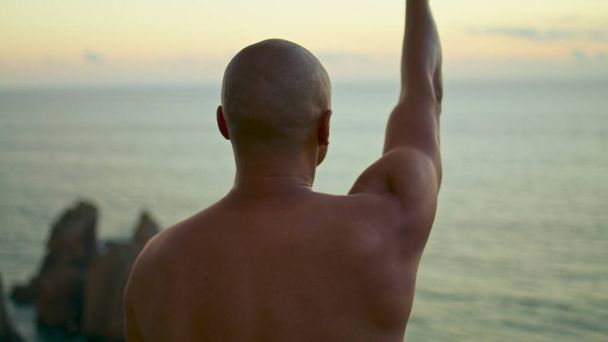 Okyanus günbatımı manzarasında kollarını açan kaslı bir adam. Sporcu dışarıda el kilidi açıyor. Bilinmeyen uygun Yogi nefesi denizde ruhani uygulamalar yapıyor. Sakin akşam egzersizi konsepti - Fotoğraf, Görsel