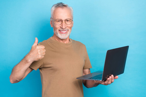 Photo of positive pensioner senior stylish guy hold netbook enjoy using modern technology isolated on blue color background. - Фото, зображення