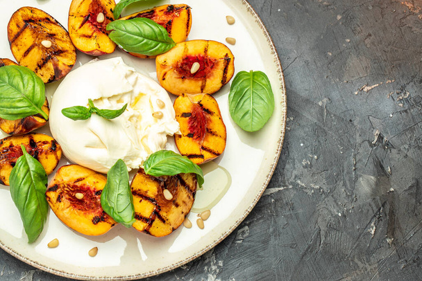 Burrata soft cheese and grilled peaches with basil and pine nuts, drizzled honey, Food recipe background. Close up, - Photo, image