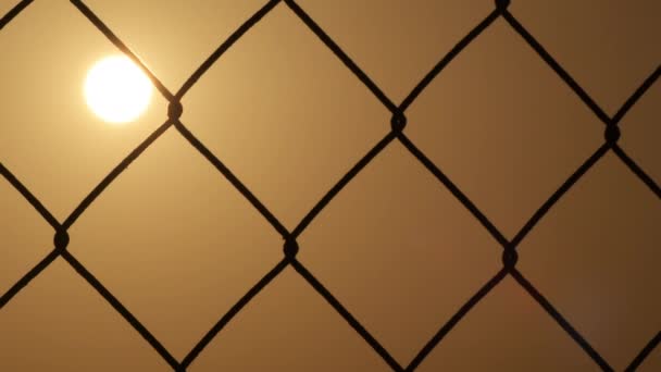 Проволочный забор с солнцем, заходящим на закате. Время покажет - Кадры, видео