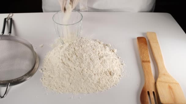 chef misurando la farina, versando farina in tazza, facendo impasto per il pane - Filmati, video