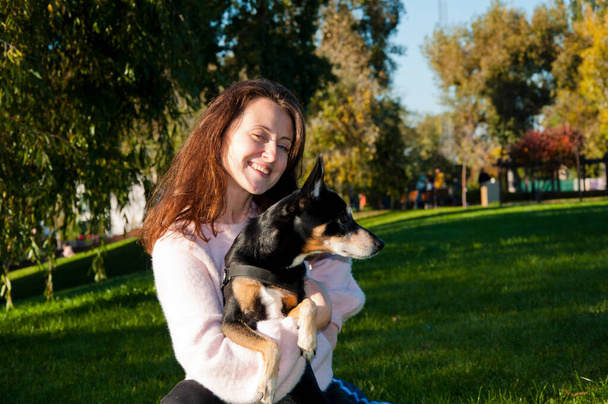 portret van gelukkige herfstvrouw houden van haar hond. vrouw knuffelen hond in de herfst park buiten. vriendschap van vrouw en hond. vrouw adopteren hond buiten. - Foto, afbeelding