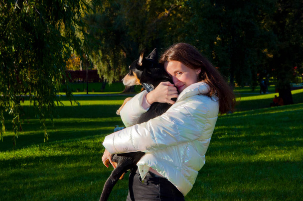счастливая женщина обнимает собаку на открытом воздухе в осеннем парке. дружба женщины и собаки. женщина усыновляет собаку снаружи. Осенняя женщина любит свою собаку. - Фото, изображение