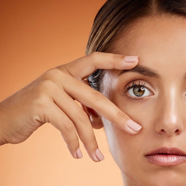 Vision, eye and beauty with face of woman for health awareness, awake and idea in orange background. Youth, cosmetics and inspiration with girl and zoom in stare for intense, serious or humanity. - 写真・画像