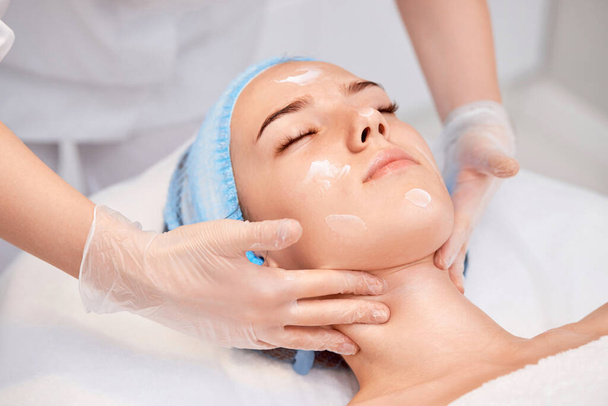young beautiful woman receiving facial massage at spa salon - Foto, afbeelding
